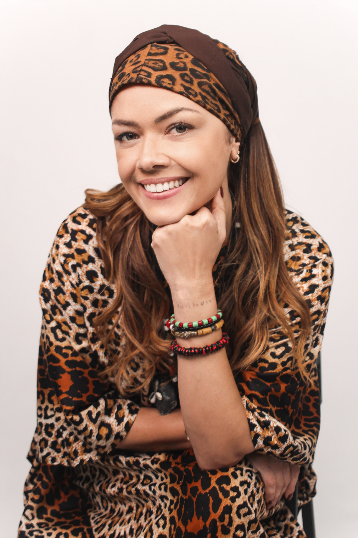 Retrato de Mãe Kátia sorrindo, com turbante e estampa de oncinha